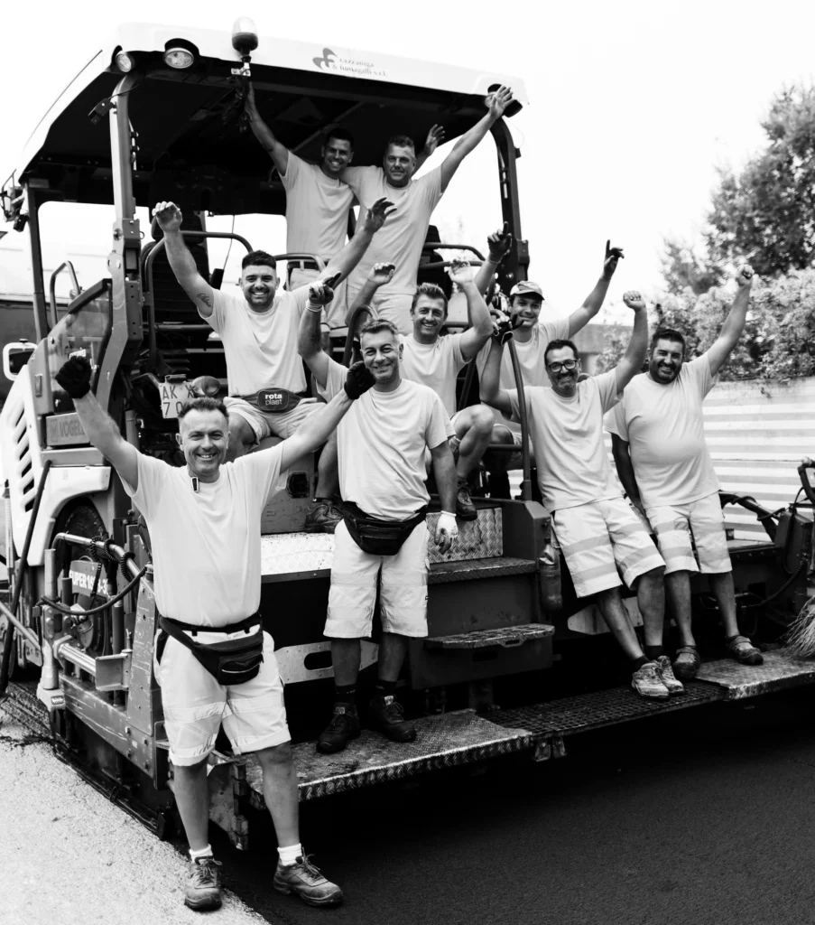 Squadra di operai in divisa posa sorridente su mezzo da lavoro