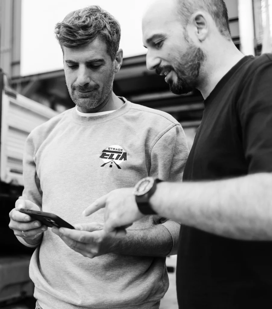 Tecnici discutono un progetto su uno smartphone in cantiere